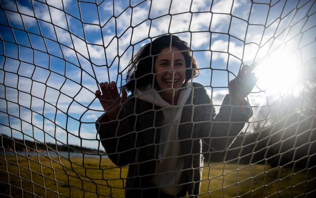 Foto ritratto di una donna felice che guarda attraverso una rete sportiva