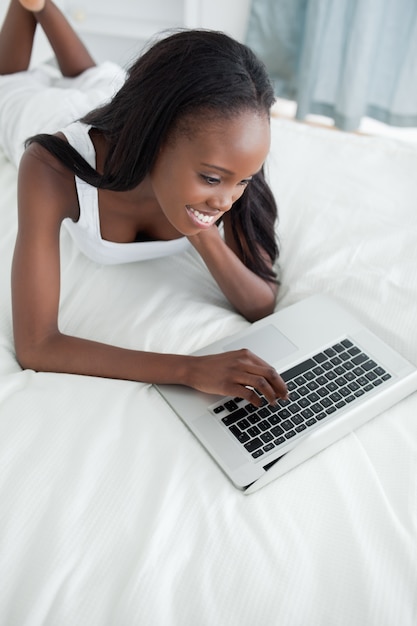 Portrait of a happy woman lying on her belly using a notebook