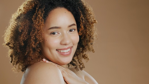 Foto ritratto di donna felice spazio mockup di bellezza naturale o cosmetici per il benessere in studio con sorriso orgoglio di luminosità della pelle o modello femminile biraziale fiducioso con risultati di cura della pelle su uno sfondo marrone