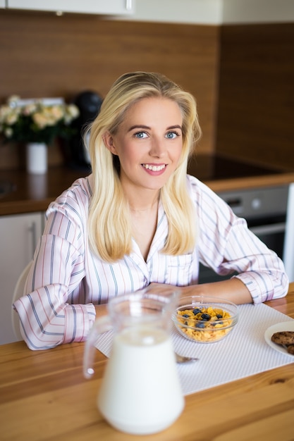 Портрет счастливой женщины в пижаме, сидящей на современной кухне