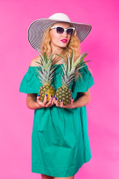 Foto ritratto di donna felice e ananas su sfondo rosa. estate, dieta e stile di vita sano