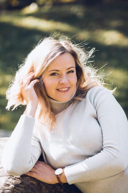 Portrait of happy woman sitting in autumn city park on sunny day closeup adult lady in casual clothe