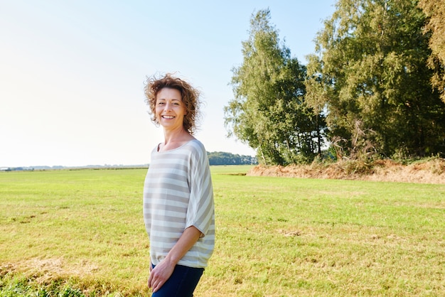 Portrait of happy woman standing in beautiful countryside