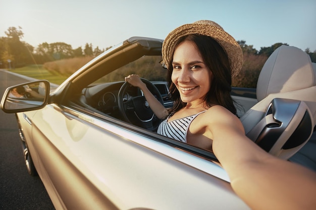 Portrait of happy woman taking selfie sitting in the car