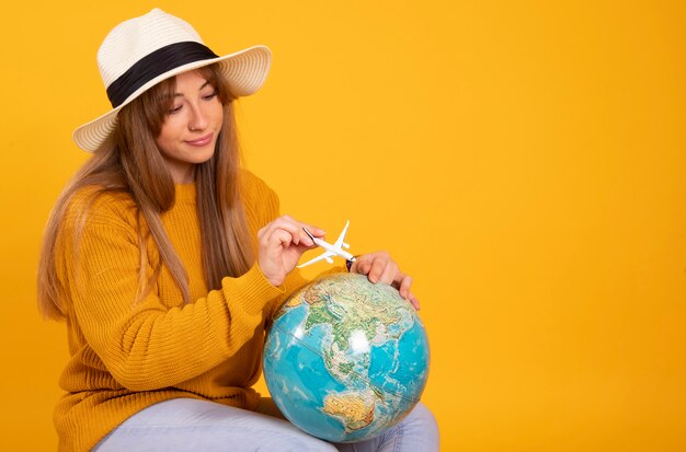 Photo portrait happy woman, traveler with a globe and suitcase, on yellow space