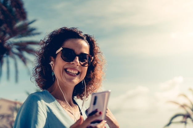 空に向かって携帯電話を使っている幸せな女性の肖像画