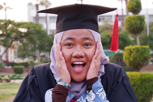 Foto ritratto di una donna felice che indossa un abito da laurea nel campus