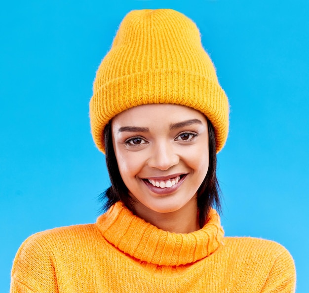 Portrait of happy woman in winter fashion with beanie jersey and isolated on blue background Style happiness and gen z girl in studio backdrop with smile on face and warm clothing for cold weather