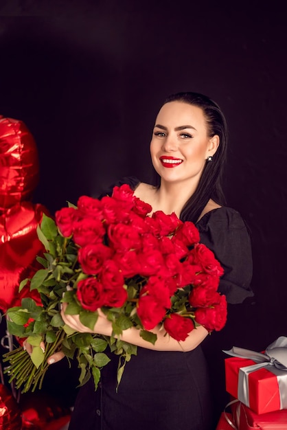 Portrait of a happy woman with a large bouquet of red roses