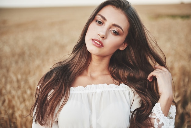 Ritratto di una donna felice con i capelli lunghi che si trova nel campo di grano