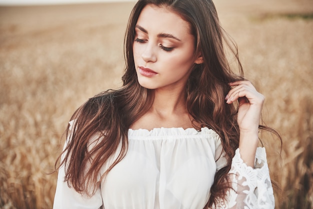 Portrait of a happy woman with long hair that is in the field of wheat