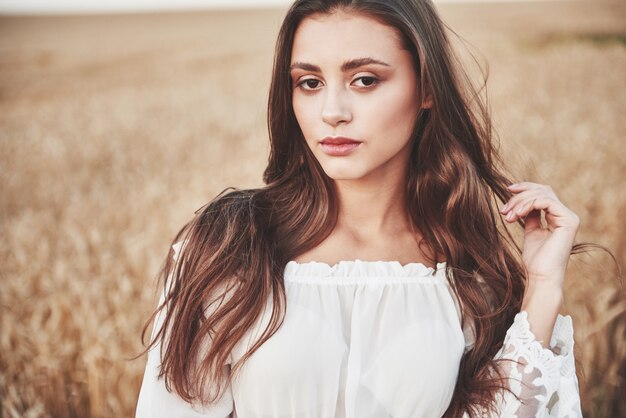 Portrait of a happy woman with long hair that is in the field of wheat