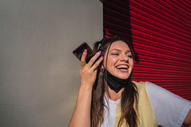 Portrait of a happy woman with a protective mask talking from a smartphone