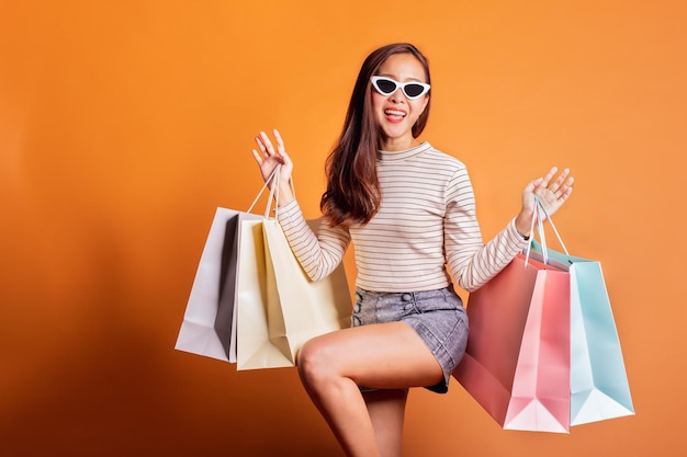 Photo portrait of happy woman with shopping bags standing against orange background