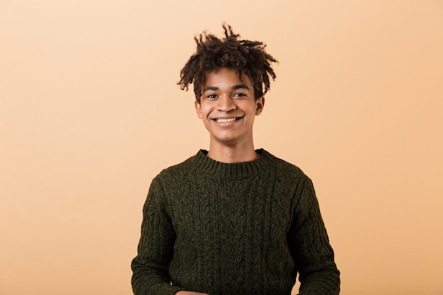 Photo portrait of a happy young africa man dressed in sweater isolated over beige wall