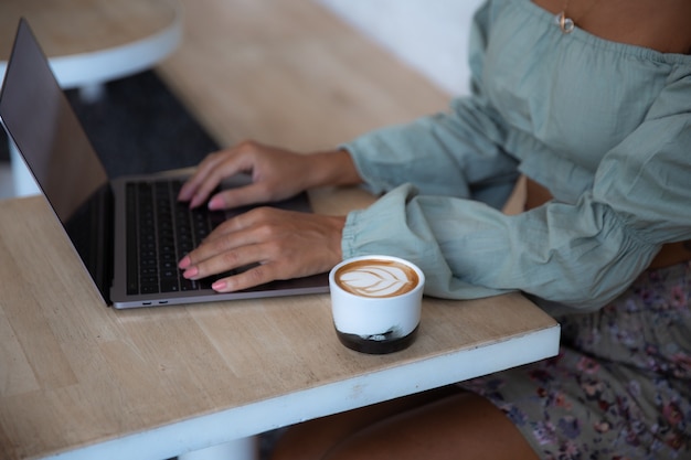 Portrait of a happy young african woman relaxing in outdoor cafe and using a laptop. remote work