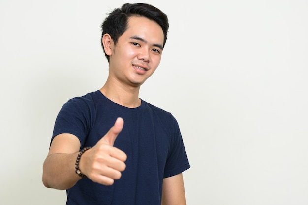 엄지 손가락을 포기하는 행복 한 젊은 아시아 남자의 초상화
