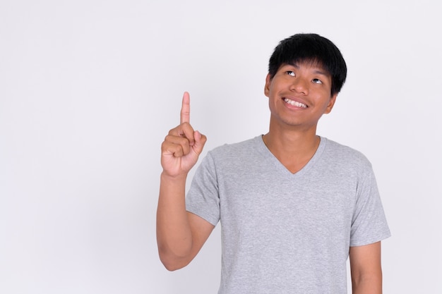 Portrait of happy young Asian man thinking and pointing up