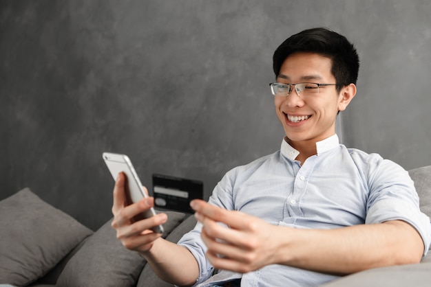 Portrait of a happy young asian man using mobile phone