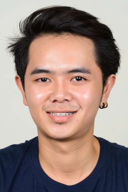 Portrait of happy young Asian man with braces smiling