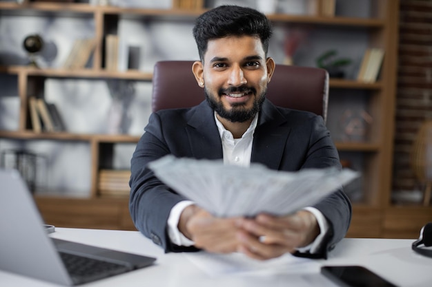 Portrait of happy young attractive male accountant holding cash banknotes counting money