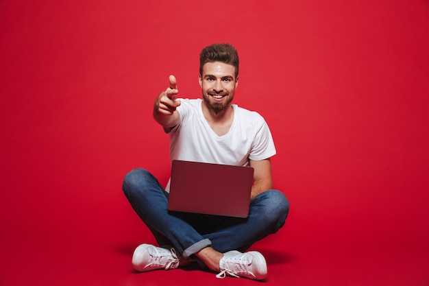 Photo portrait of a happy young bearded man pointing at front