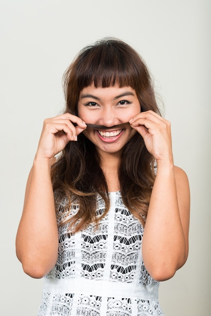 Photo portrait of happy young beautiful asian woman with hair as mustache