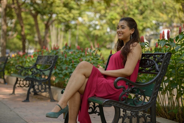 公園に座っている幸せな若い美しいインドの女性の肖像画