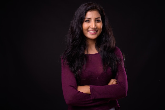 Portrait of happy young beautiful Indian woman smiling with arms crossed