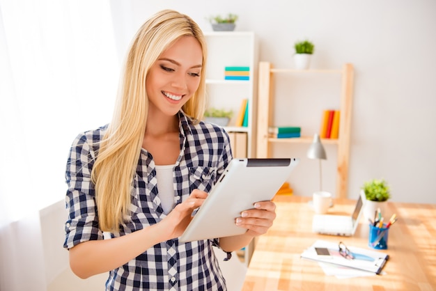 Portrait of happy young blonde using digital tablet in office