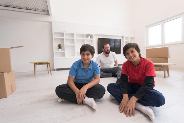 portrait of happy young boys with their dad sitting on the floor in a new modern home