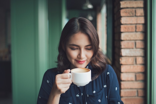 レストランで朝コーヒーを飲む手にマグカップを持つ幸せな若いビジネス女性の肖像画