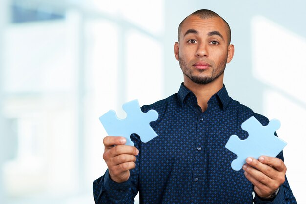 Portrait Of A Happy Young Businessman Holding Jigsaw Puzzle