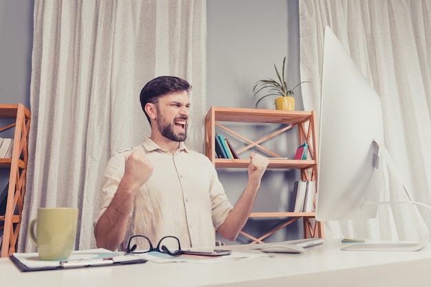 Portrait of happy young businessman triumphing and showing fists