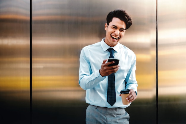 Portrait of a Happy Young Businessman Using Mobile Phone in the Urban City.