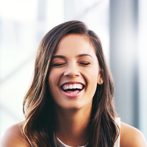 Portrait of a happy young businesswoman laughing in a modern office