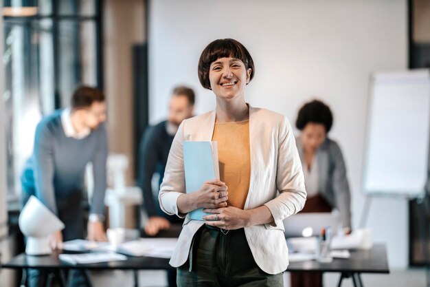 Portrait of a happy young businesswoman smiling at the camera while standing at the office