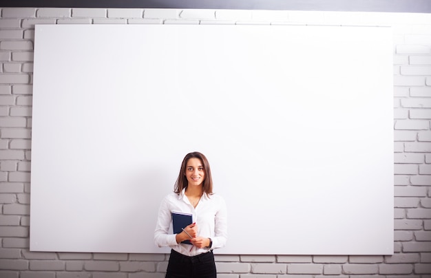 白い壁の近くの幸せな若い実業家の女性の肖像画。