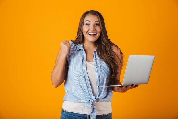 Portrait of a happy young casual woman, holding laptop computer