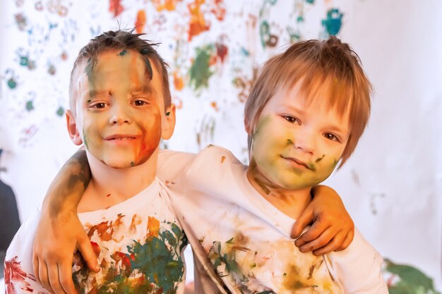 Ritratto di bambino felice che gioca con l'acquerello. viso di bambino e vestiti disordinati dipinti con vernici. concetto di divertimento per bambini, giochi d'arte e teppismo. immagine a colori per il festival di holi. copia spazio