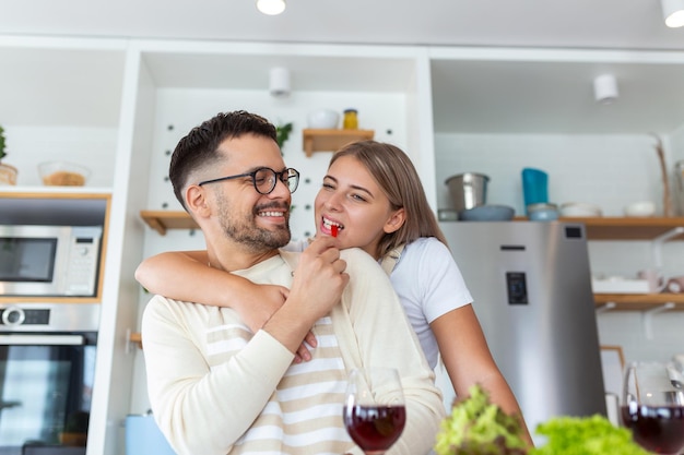 Ritratto di giovane coppia felice che cucina insieme in cucina a casa romantica la giovane donna attraente e l'uomo bello si divertono a trascorrere del tempo insieme stando in piedi su una cucina moderna e leggera