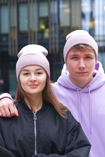 Портрет счастливой молодой пары в шляпах на открытом воздухе, позирующей в городской уличной одежде