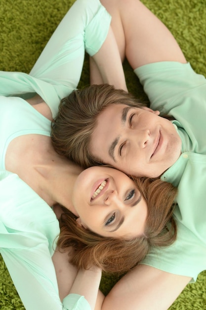 Portrait of happy young couple in love lying on floor at home