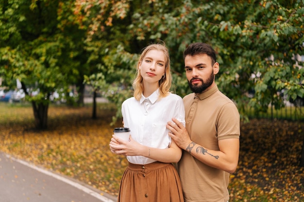 Portrait of happy young couple in love standing holding hands on city park looking at camera