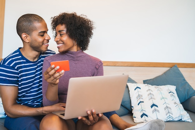 Portrait of happy young couple shopping online with credit card and laptop at home. Shop online and relationship concept.