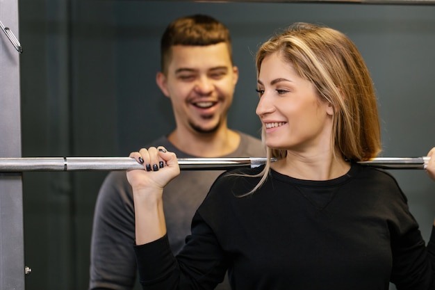 Portrait of a happy young couple in sporty outfits lifting some weights and working out together in gym. Sporty Gym Concept.