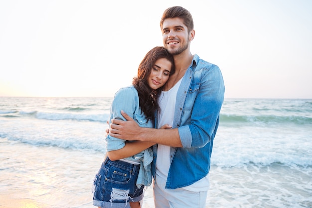 Portrait of happy young couple standing and hugging on the beach