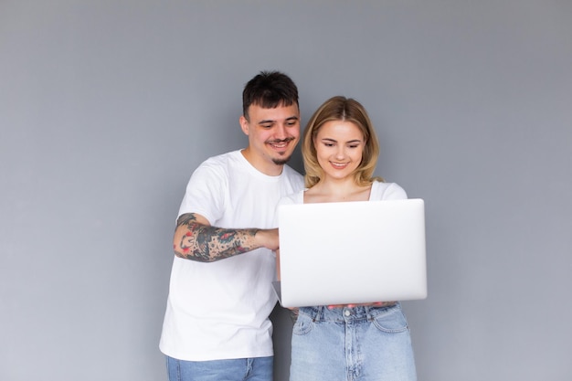 Portrait of happy young couple using laptop isolated on gray background