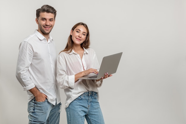 Ritratto di giovane coppia felice che utilizza computer portatile su fondo bianco