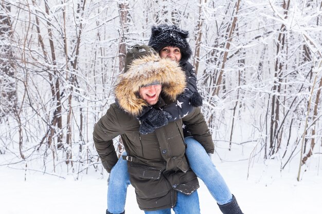 Portrait of happy young couple in winter park with their friend behind.